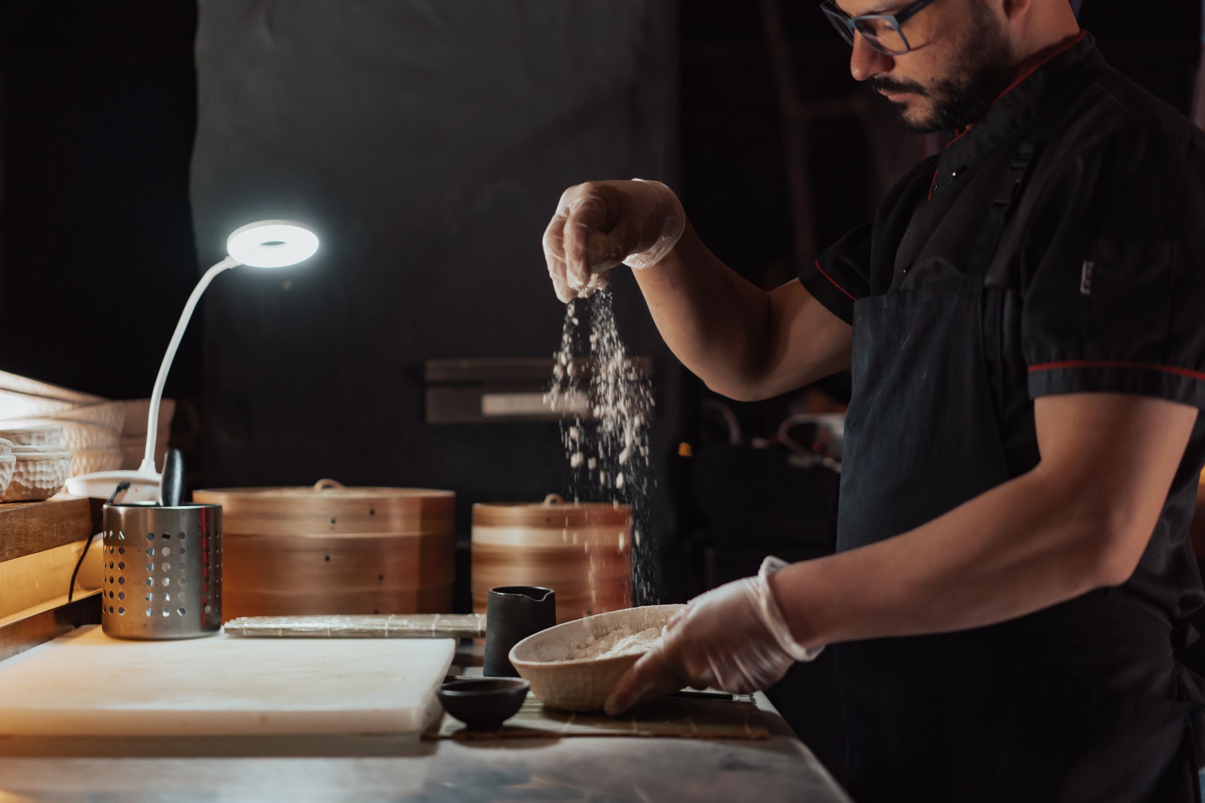 Chef sifting flour beside bamboo steamers in the Camberwell café kitchen
