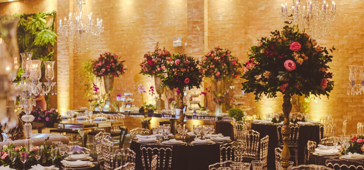 A function room set for a banquet under chandeliers and tall floral centrepieces