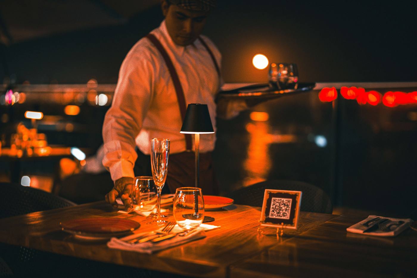 A bartender pouring drinks on a terrace at night
