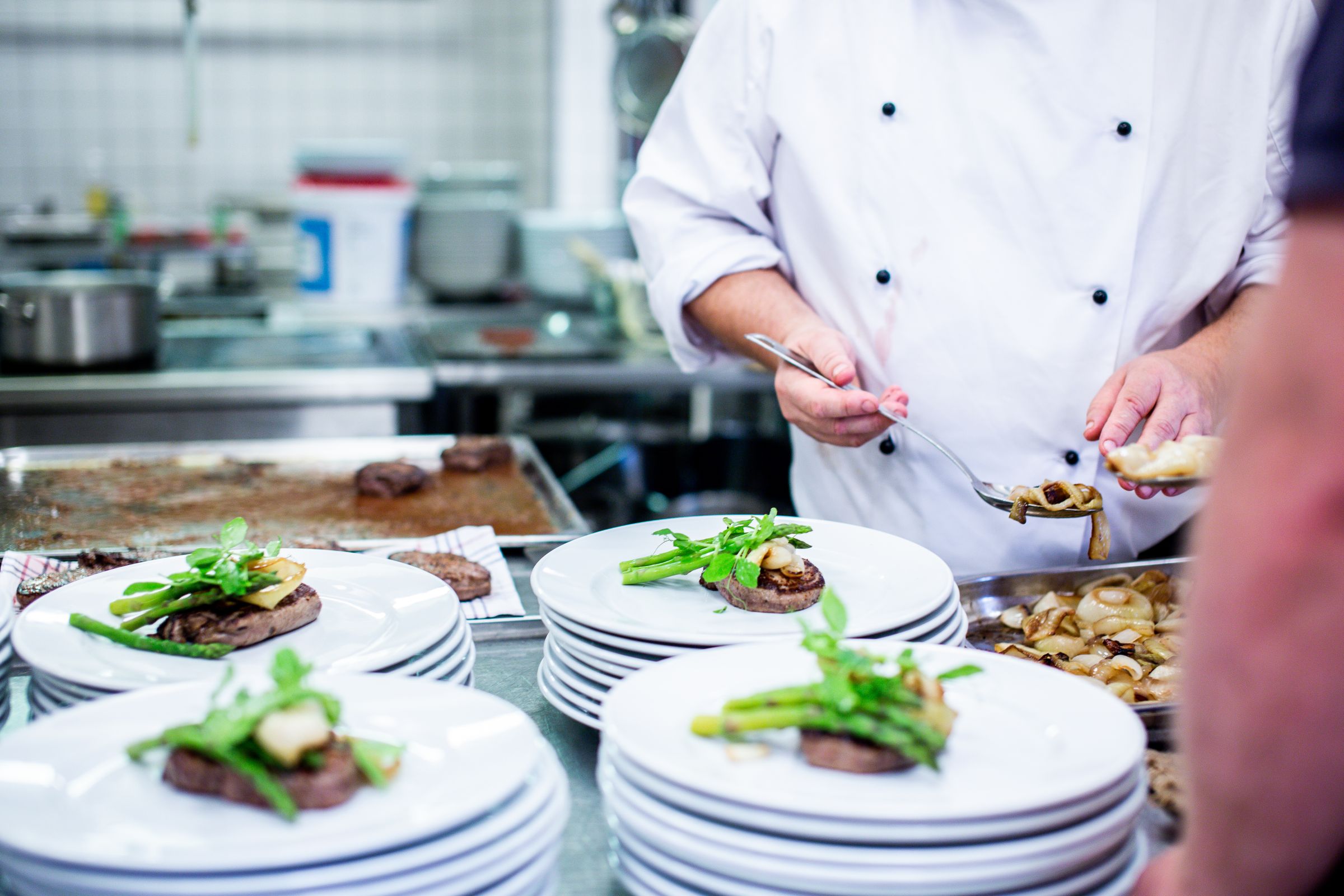 Chef plating a run of dishes at the pass