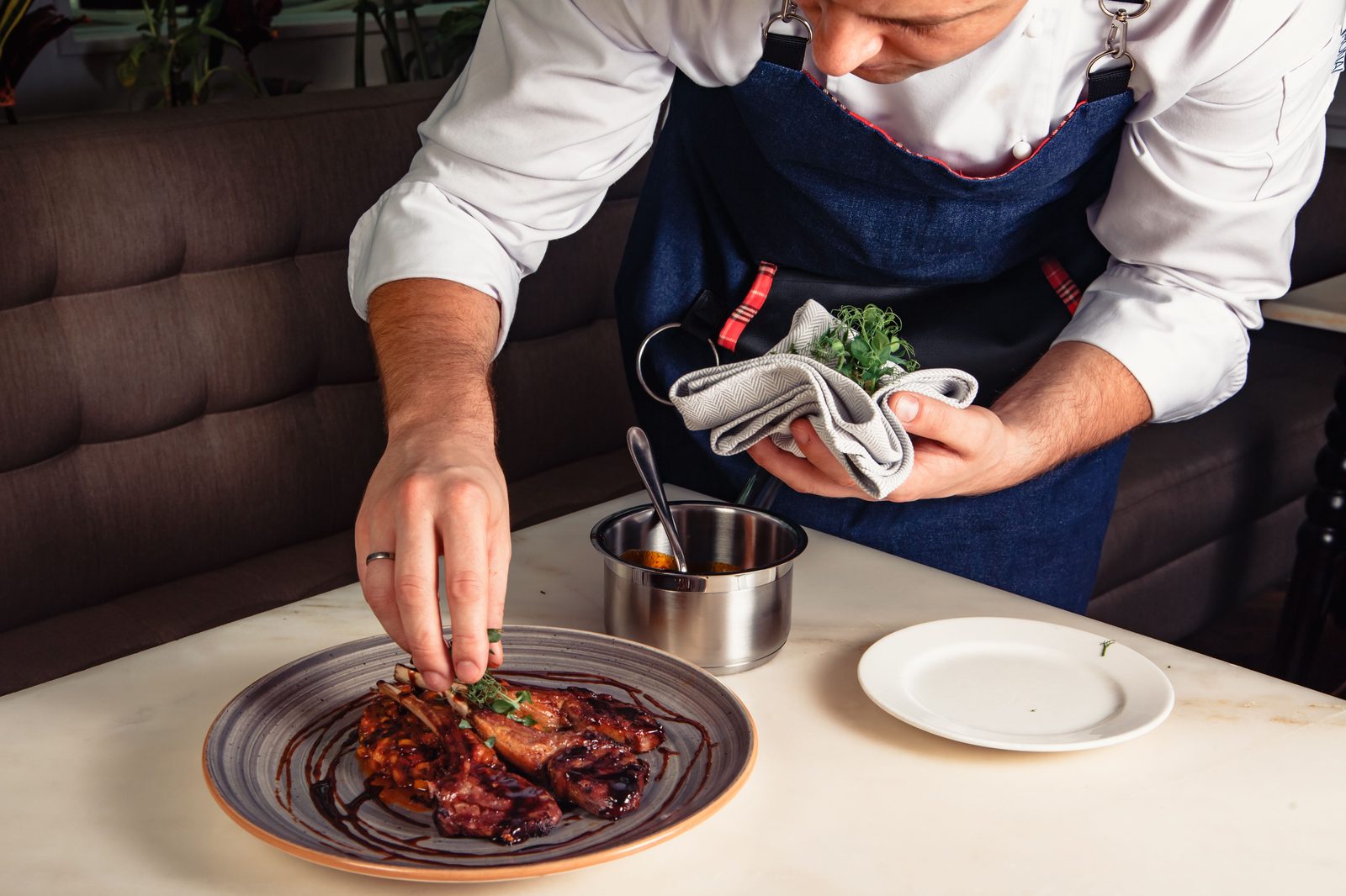 Chef finishing a plated dish with a garnish