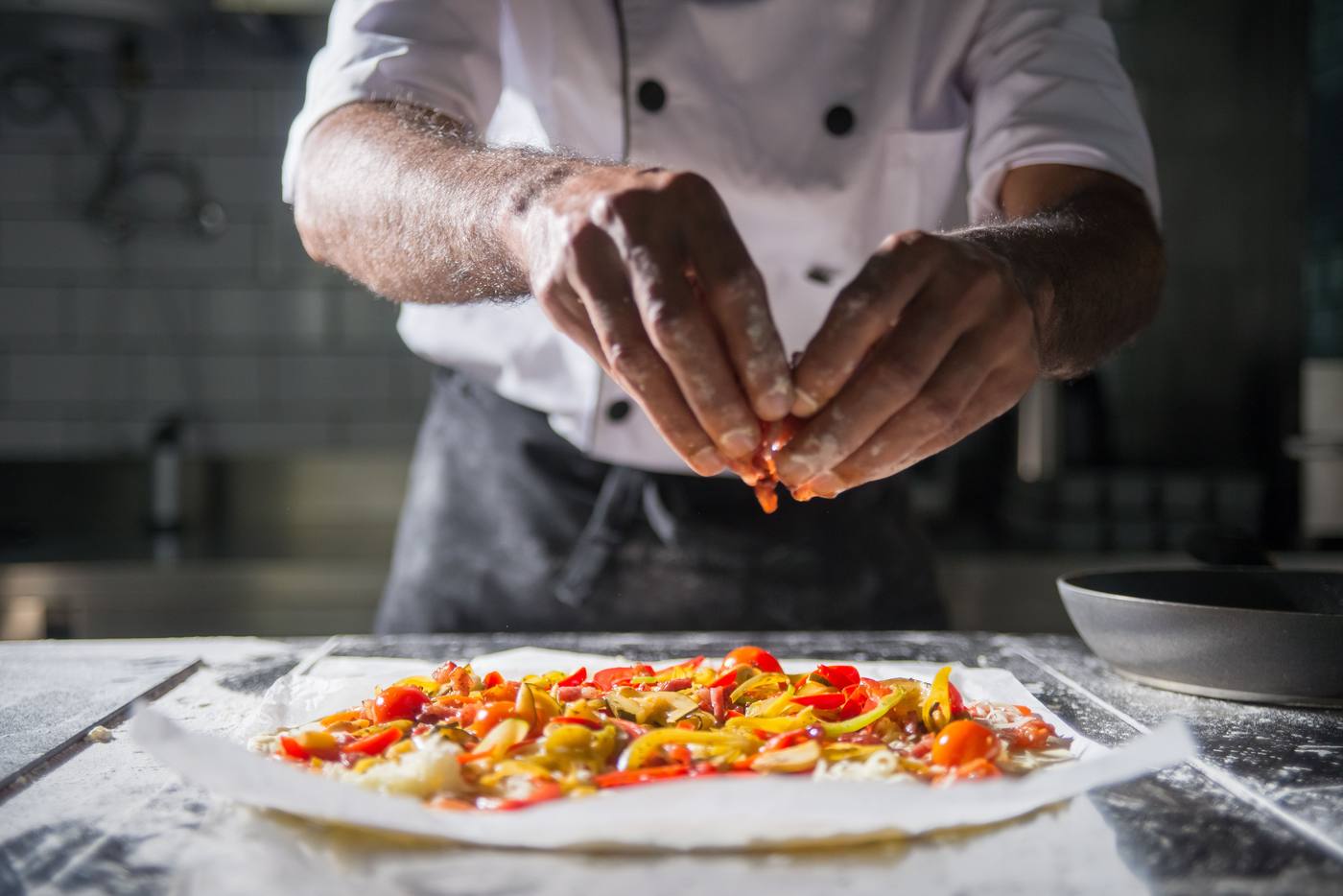 Chef finishing a dish by hand on the bench