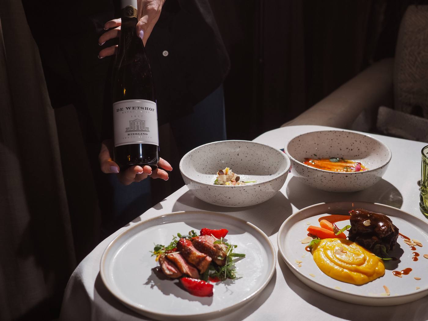 Plates and a bottle of wine being served at the table