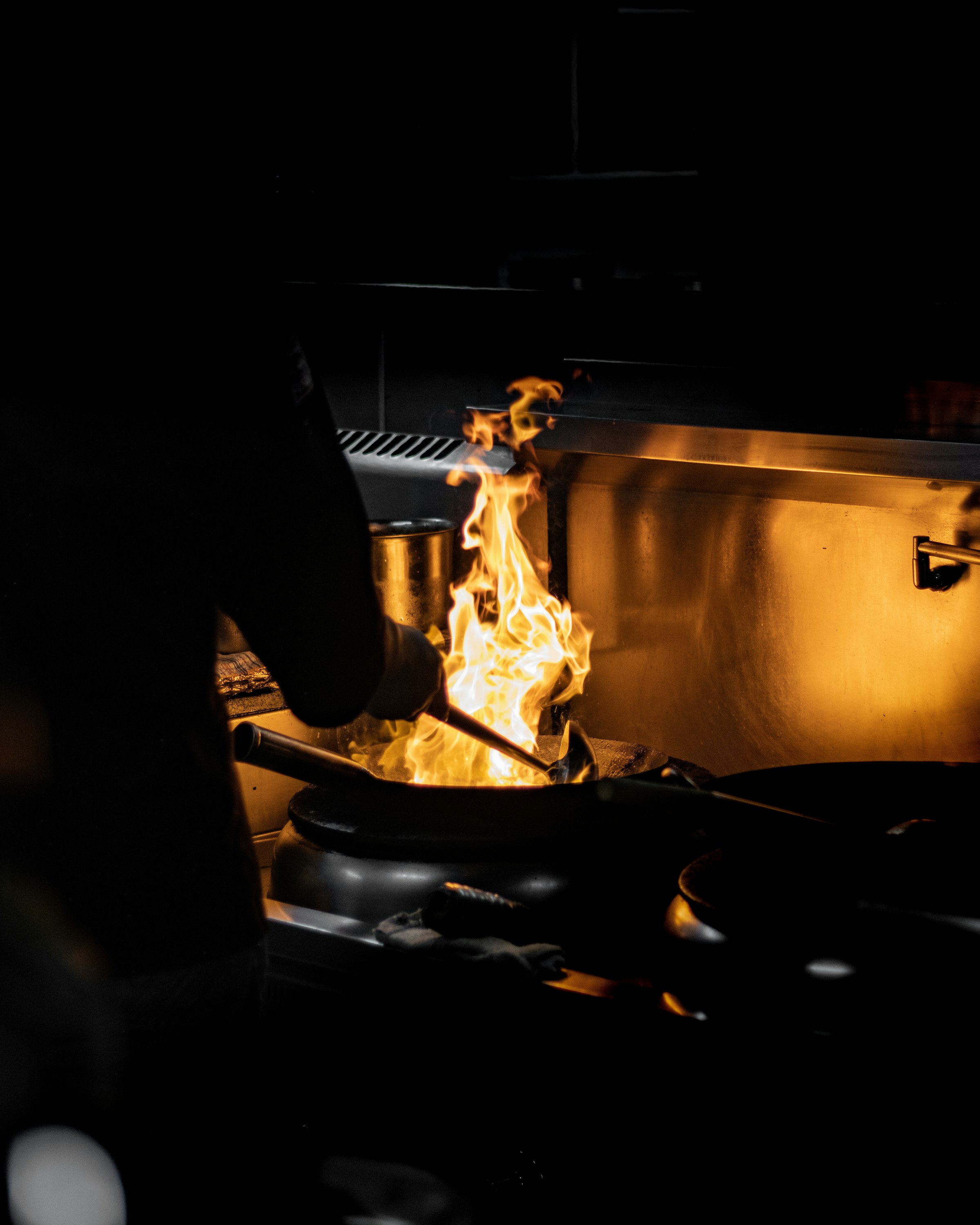 Flames rising from a pan on a busy kitchen line