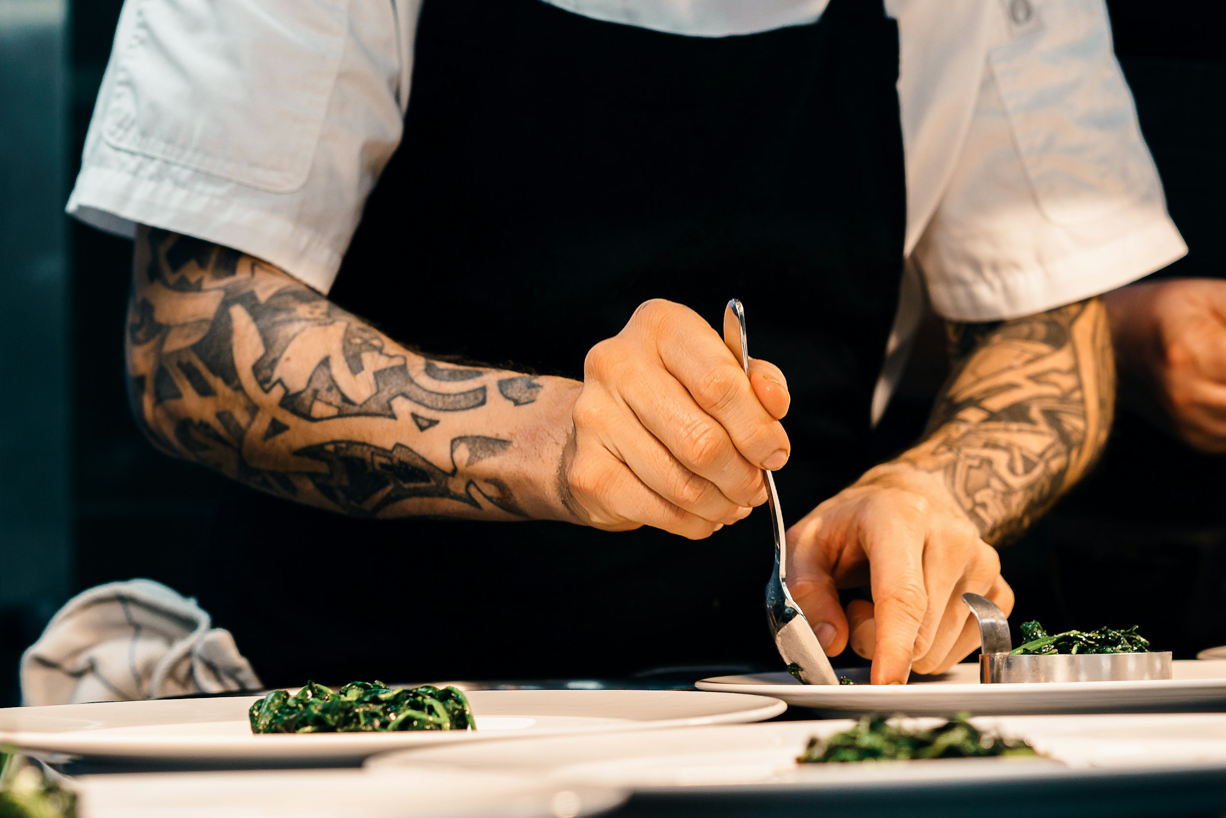 Chef garnishing plated dishes with fresh herbs in a busy kitchen