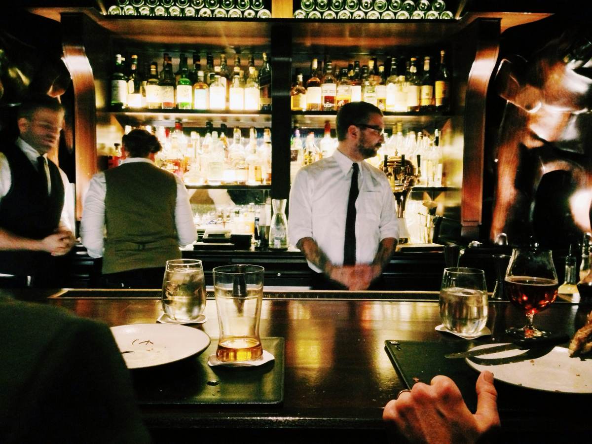 Bar staff working behind a backlit bar